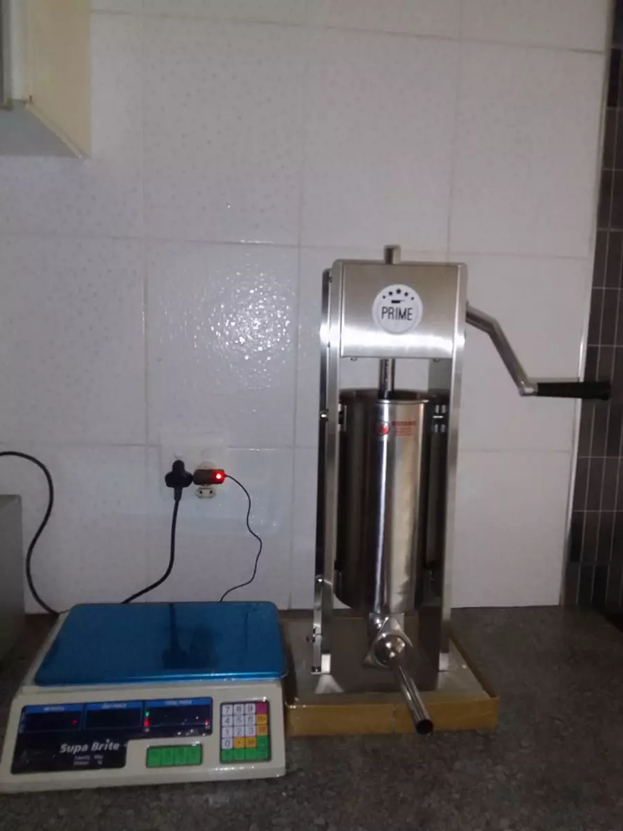Digital weighing scale and stainless steel sausage stuffer on a kitchen countertop